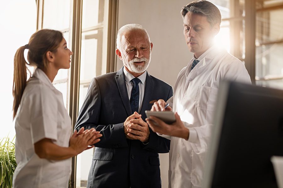 Employee Benefits - Businessman Talking to a Doctor in Medical Office