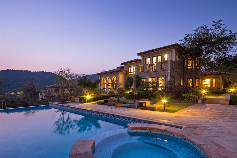 Private Client Services Insurance - View of Luxury Two Story Home with Swimming Pool in the Evening