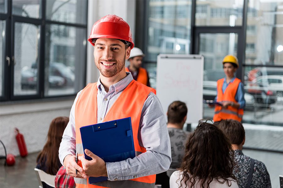 Safety Training and Certification - Portrait of a Cheerful Worker with a Clipboard Attending a Safety Presentation at Work